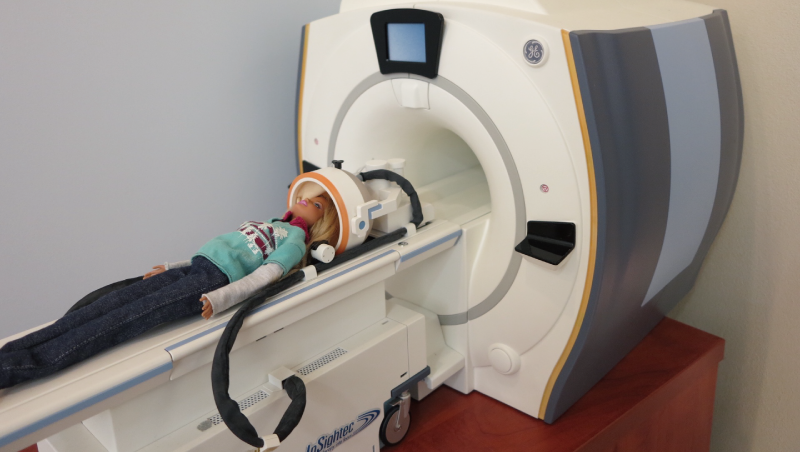 InSightec總部展示的模型，娃娃躺在自家的超音波發射與導航設備上，頭部上方的大型圈狀儀器，則是美國GE出品的MRI（核磁共振造影儀），用於定位找出要襲擊的目標。