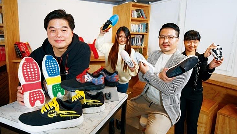 歷經品牌重生,許佳鳴(左1)將環保鞋訂為公司主軸,如桌上一紅、一藍2雙鞋底,正是以該顏色的飲料寶特瓶製作而成。 歷經品牌重生,許佳鳴(左1)將環保鞋訂為公司主軸,如桌上一紅、一藍2雙鞋底,正是以該顏色的飲料寶特瓶製作而成。