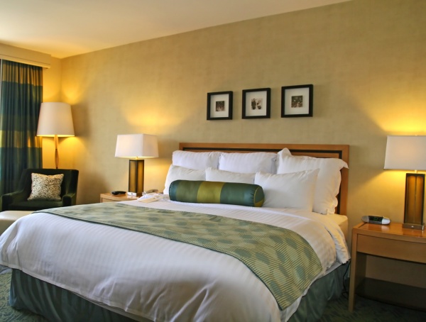 床上有多顆枕頭、鋪著床尾巾的飯店房間。