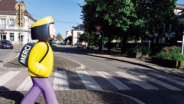 斑馬線旁，立了個背著書包的兒童雕像，似乎也正等著過馬路，書包上還用法文寫著「MERCI(謝謝)」